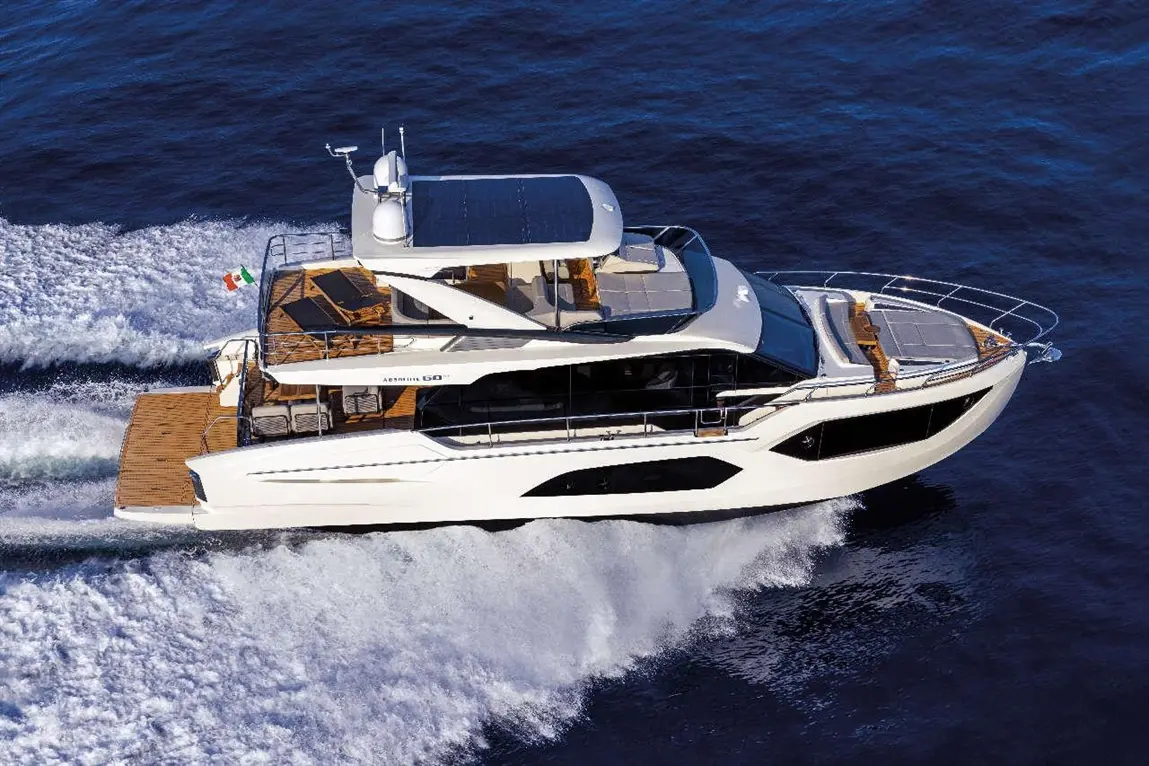 Aerial view of a white luxury yacht, 'Astonishing 60', cruising through deep blue waters with a Mexican flag flying.